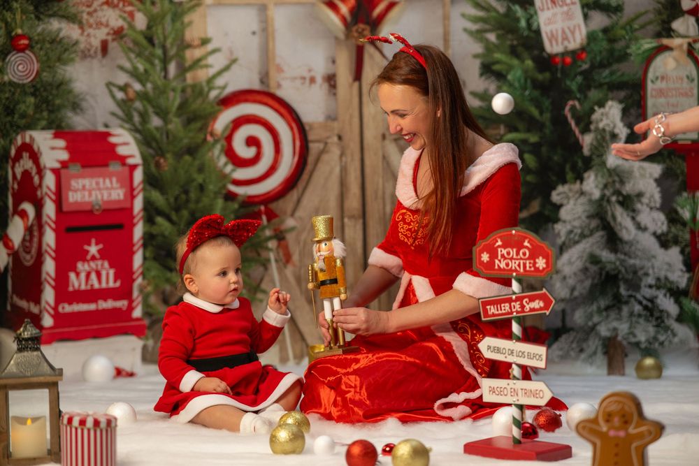 Holiday scene with red and white decor featuring a mailbox, evergreen trees, and festive Christmas decorations.