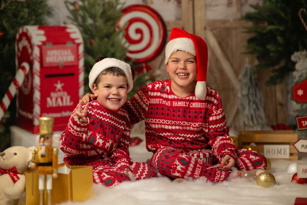 Christmas photo backdrop with red mailbox, pine trees, and festive holiday decorations in white and red theme.