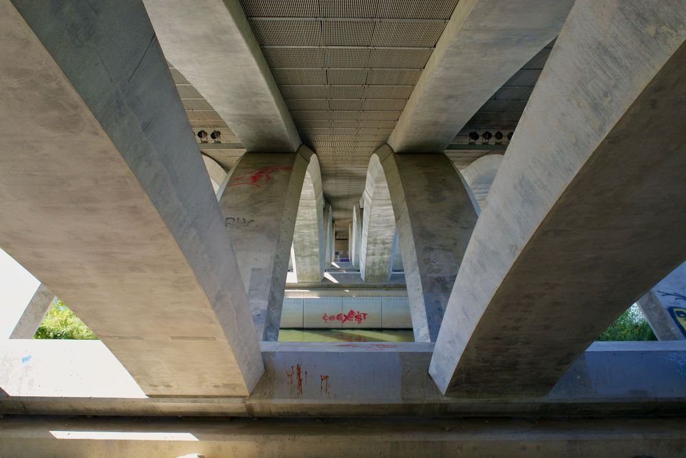 Geometric concrete bridge supports create striking angular patterns viewed from below.