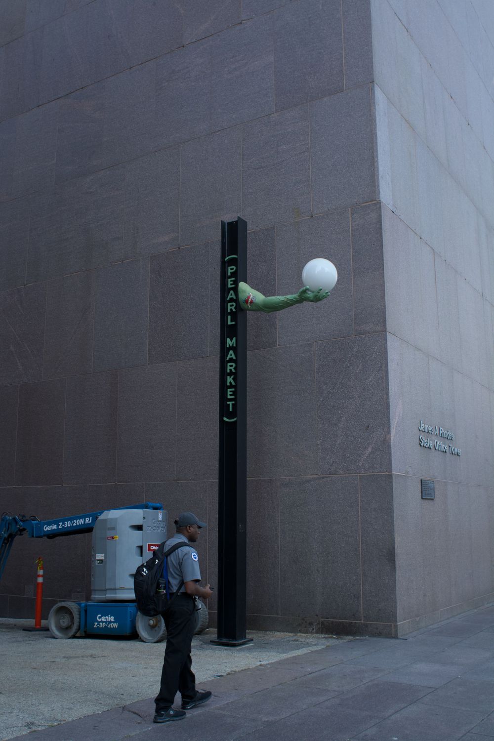 Modern street lamp with spherical white globe mounted on dark wall.