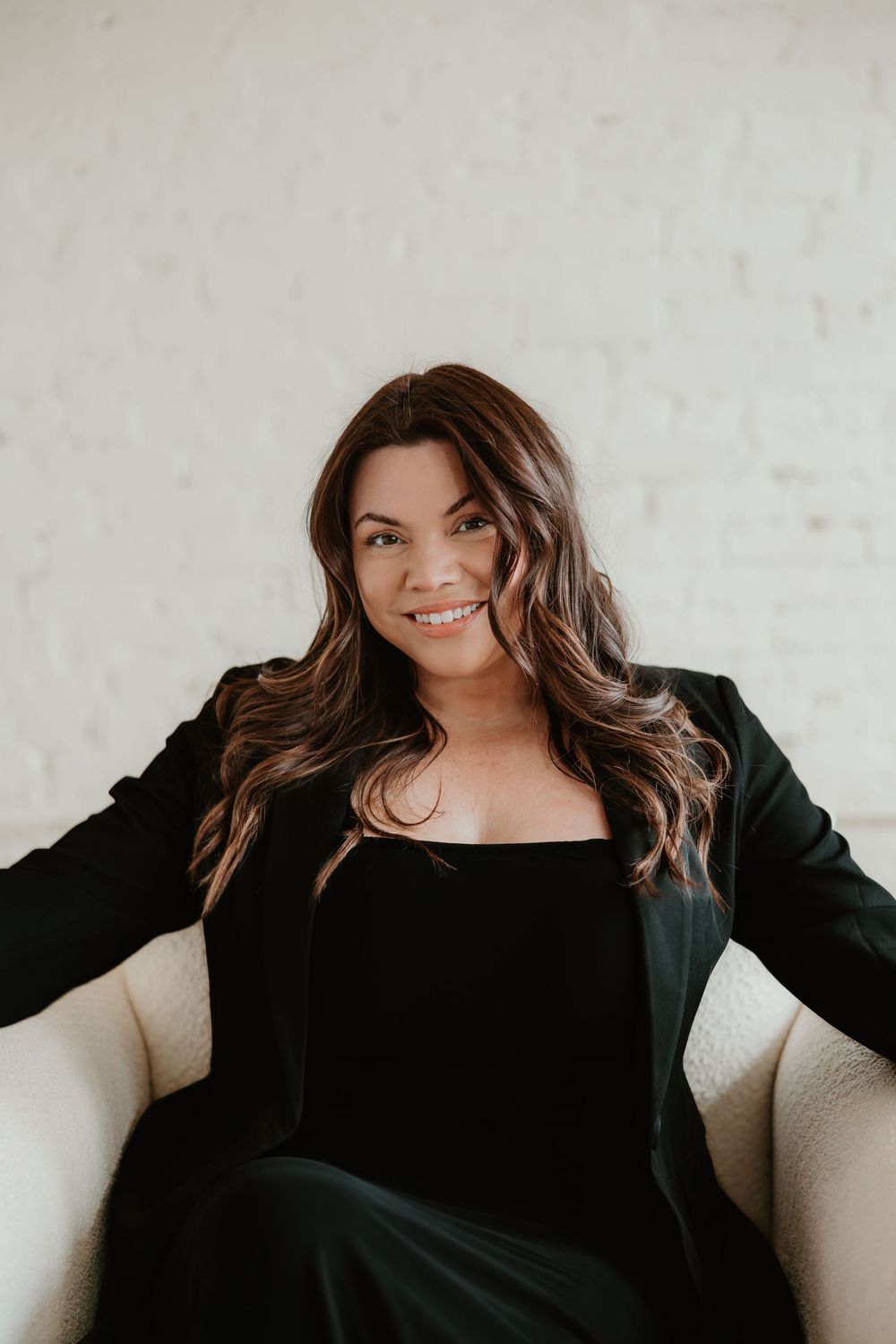A series of four professional headshot photos showing someone in a black top against a light colored wall.