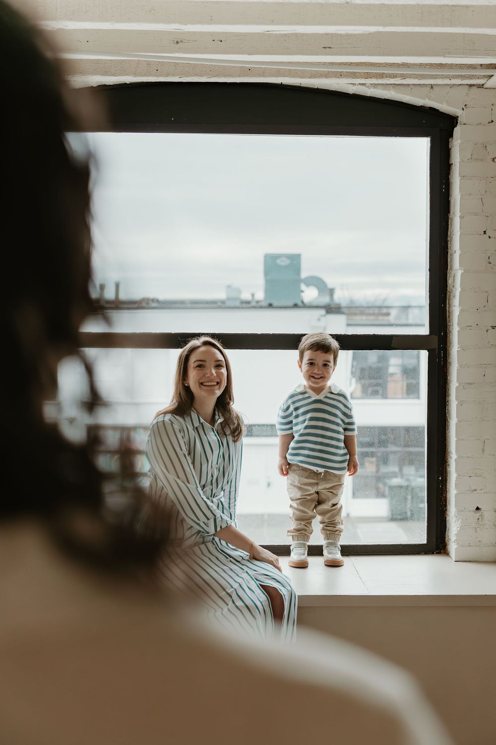 A series of candid family moments captured through a window showing playful interactions in warm natural lighting.