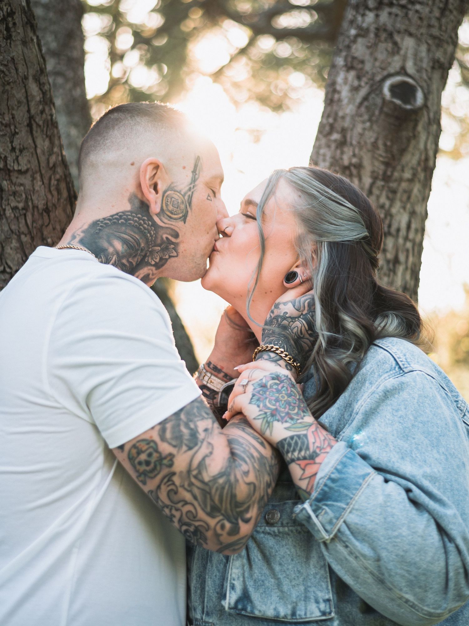 A couple shares an intimate moment on a wooden bridge during sunset.