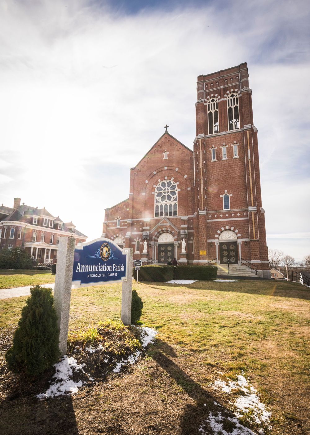 Panoramic view of a red brick church building with snow patches on the ground.