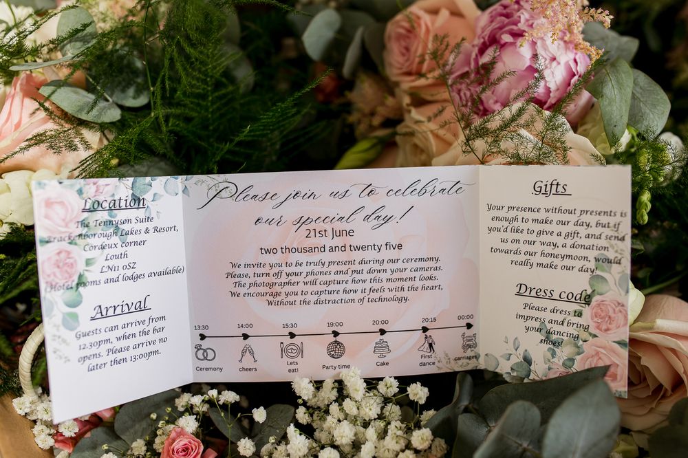 Wedding timeline card with floral decorations and schedule details surrounded by pink and white flowers.