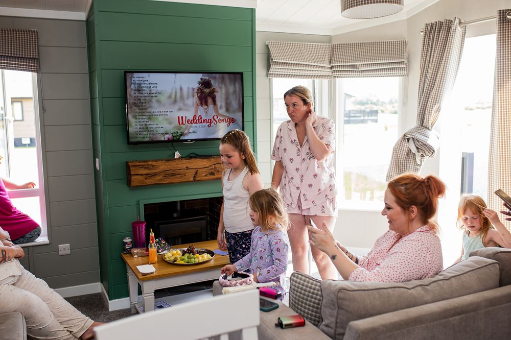 Living room scene with TV mounted on green wall while people gather on couch and around the space.