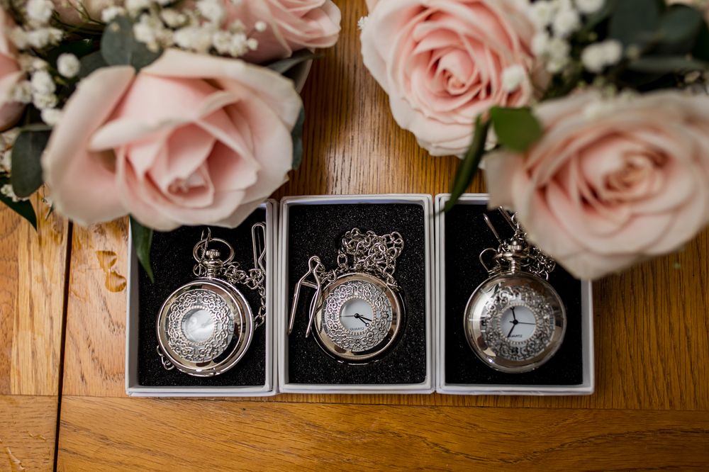 Delicate pink roses and wedding decor details arranged on wooden surface.