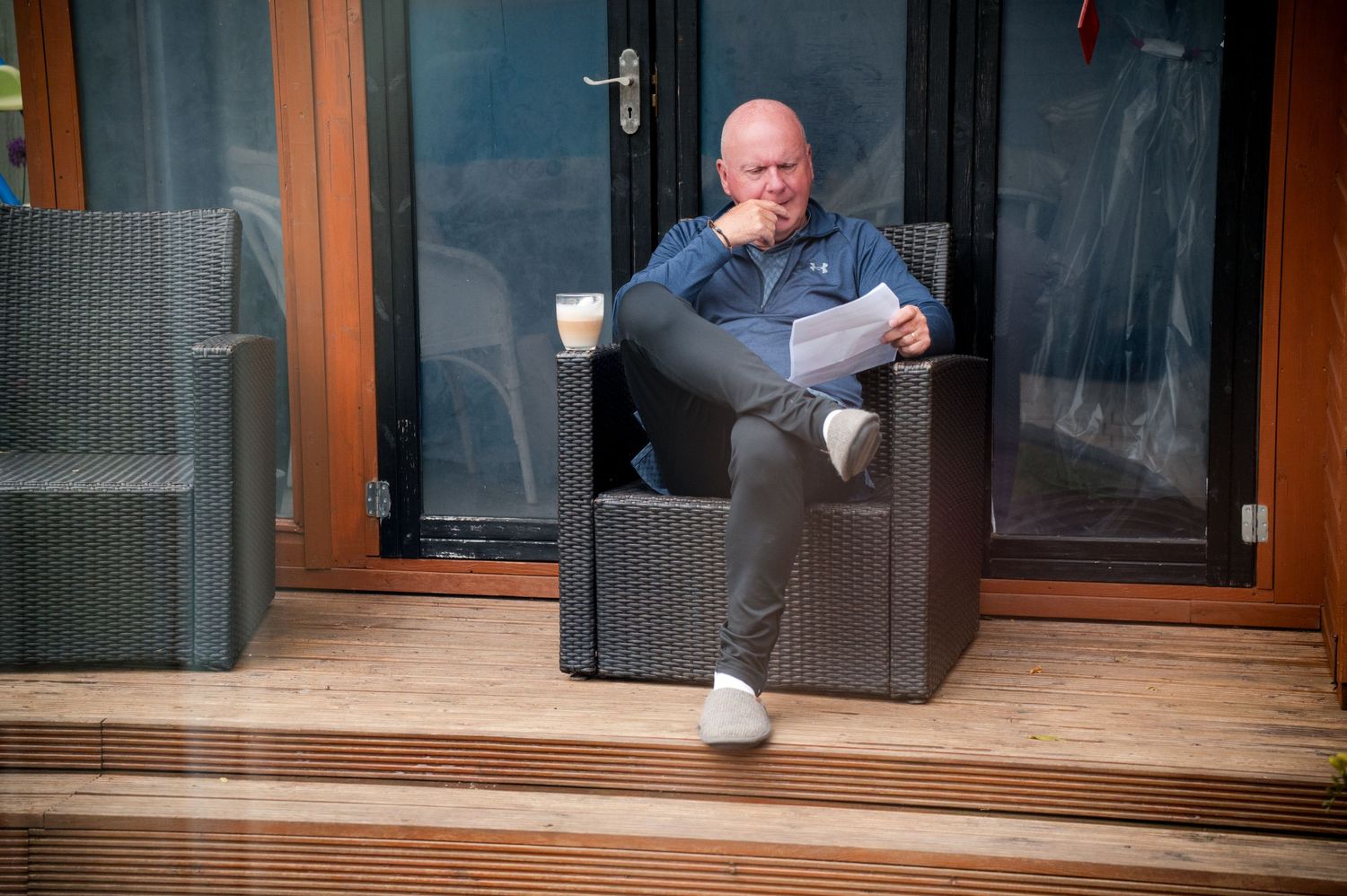 People relaxing in outdoor spa chairs with coffee cups on a wooden deck.