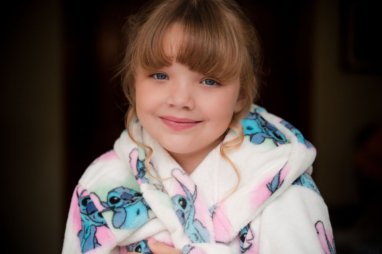 A person in a floral robe sits on a couch in a dimly lit room.