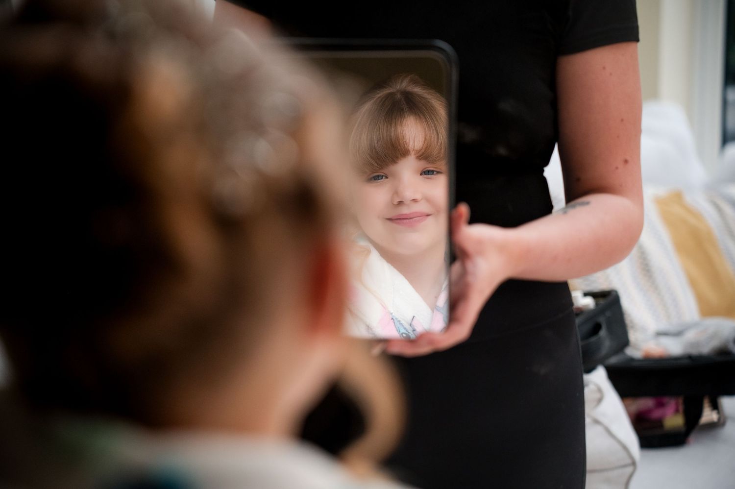 A reflection in a mirror shows someone getting their hair styled in a salon setting.