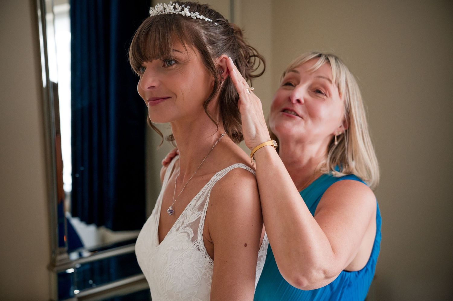 Wedding preparations show a bride in white dress getting ready with help from someone wearing blue.