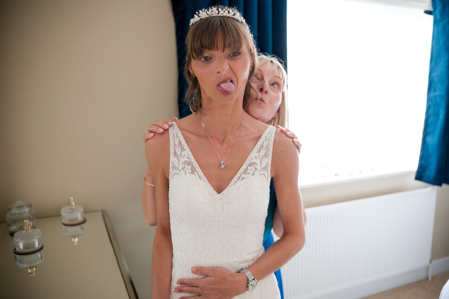 A bride in a white wedding dress looks at her reflection in a mirror while getting ready for her special day.