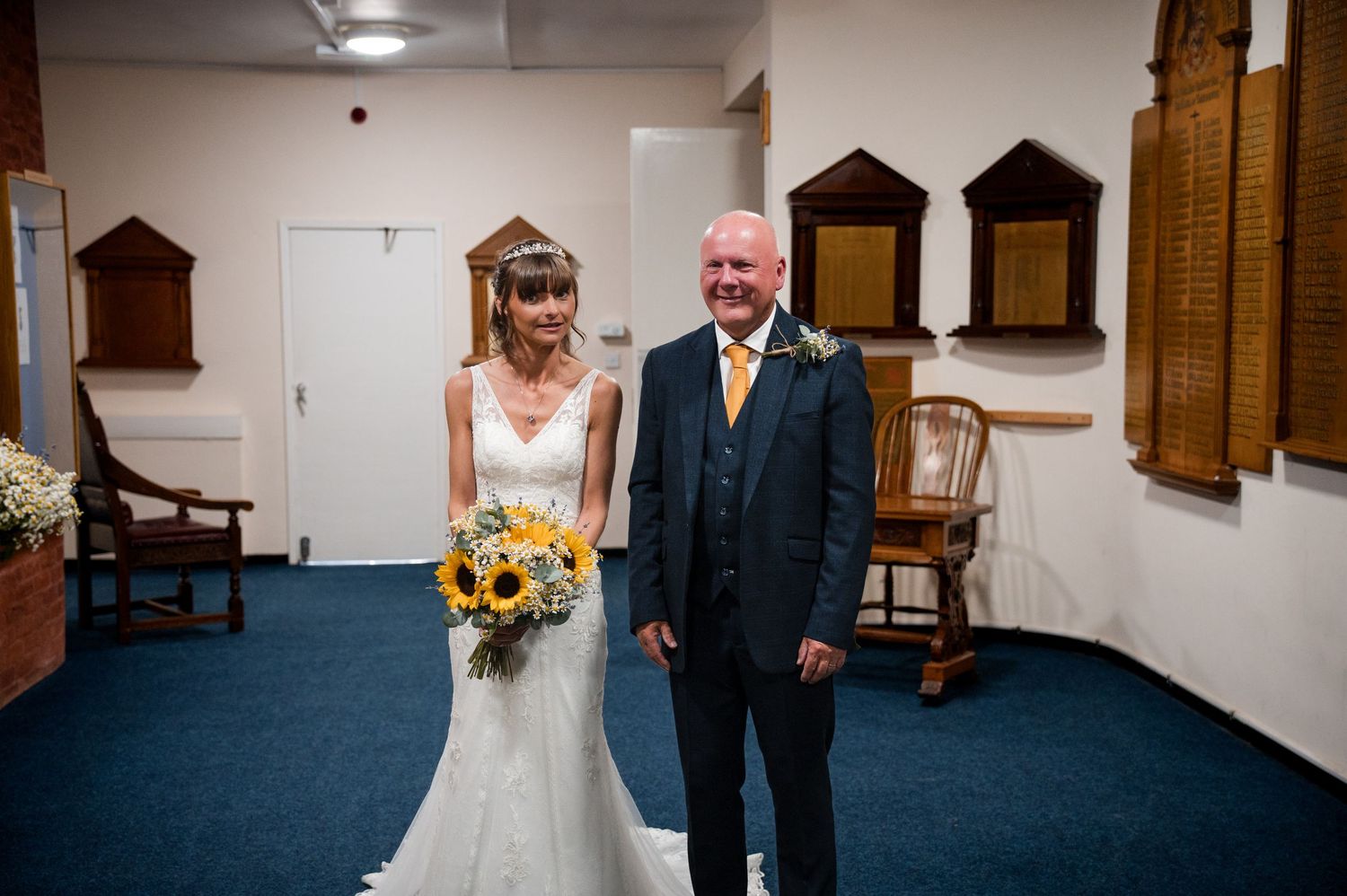 A wedding ceremony takes place in a church with dark blue carpeting and wooden accents.
