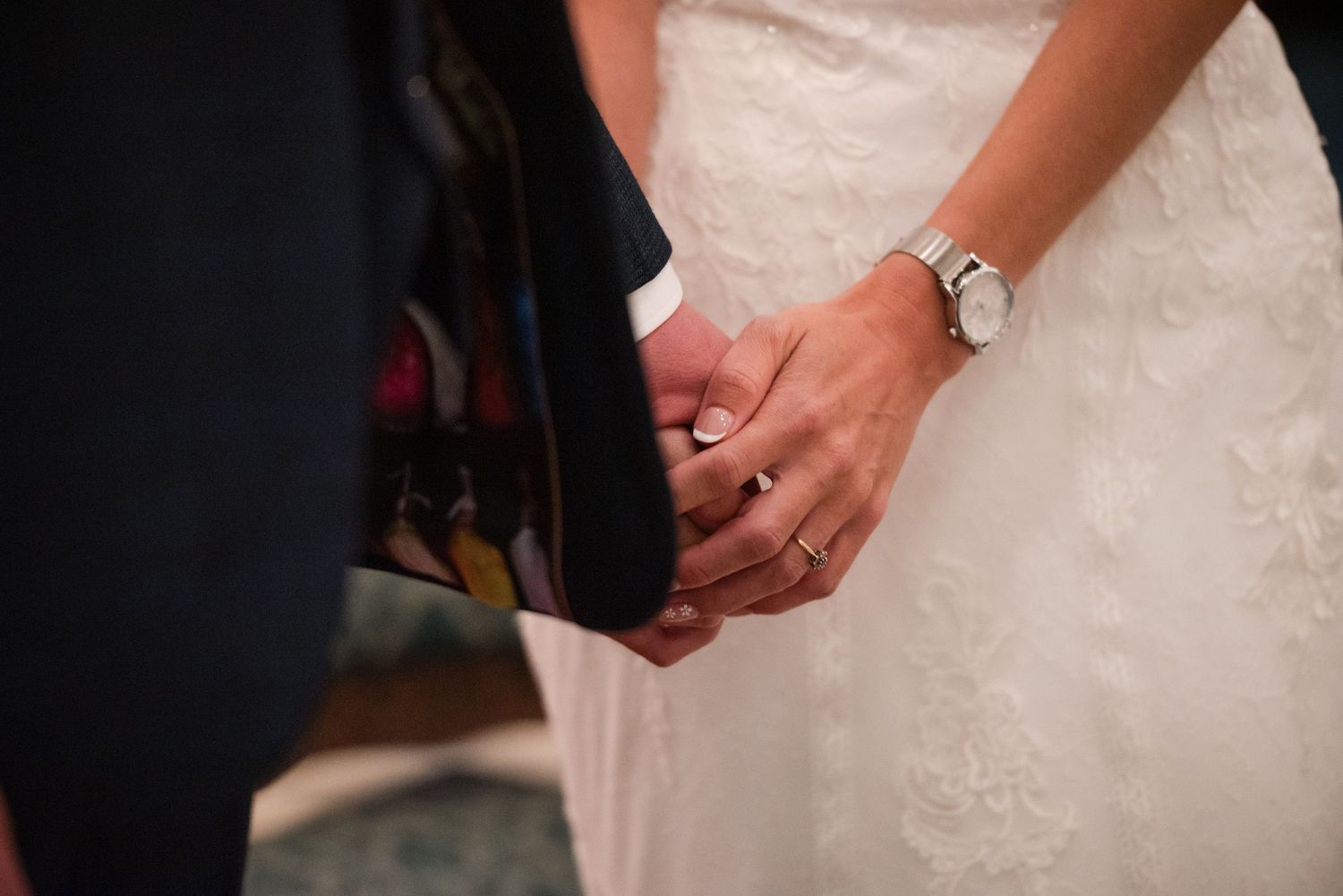 Close-up detail of hands holding wedding rings during an elegant ceremony.
