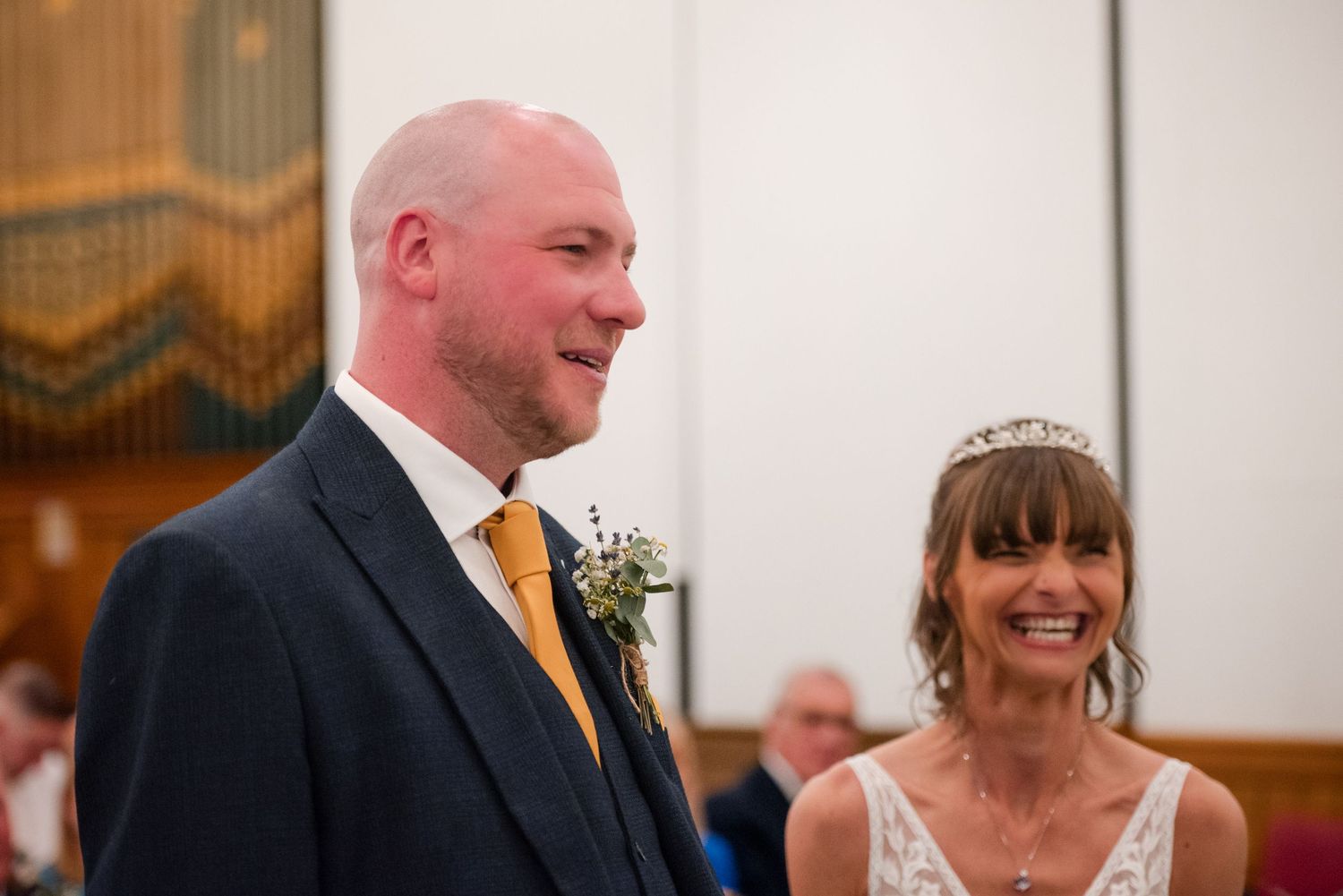 A couple shares a joyful moment during their wedding ceremony in an elegant indoor venue.