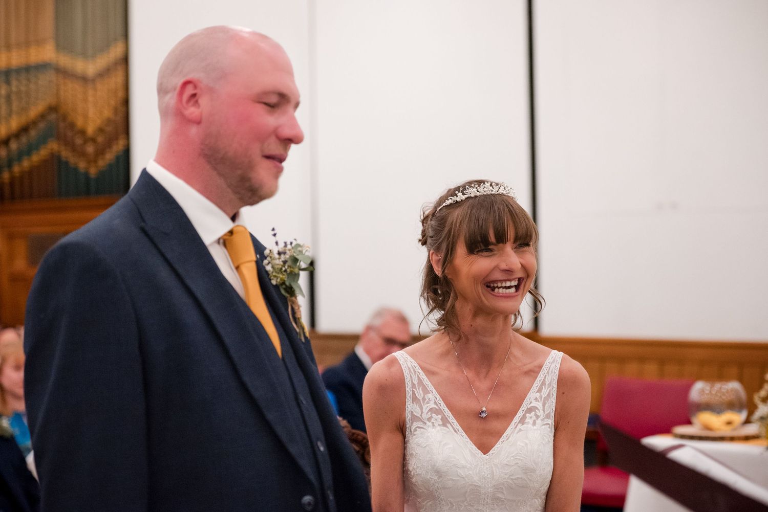 A bride and groom share a joyful moment during their wedding ceremony in a church setting.