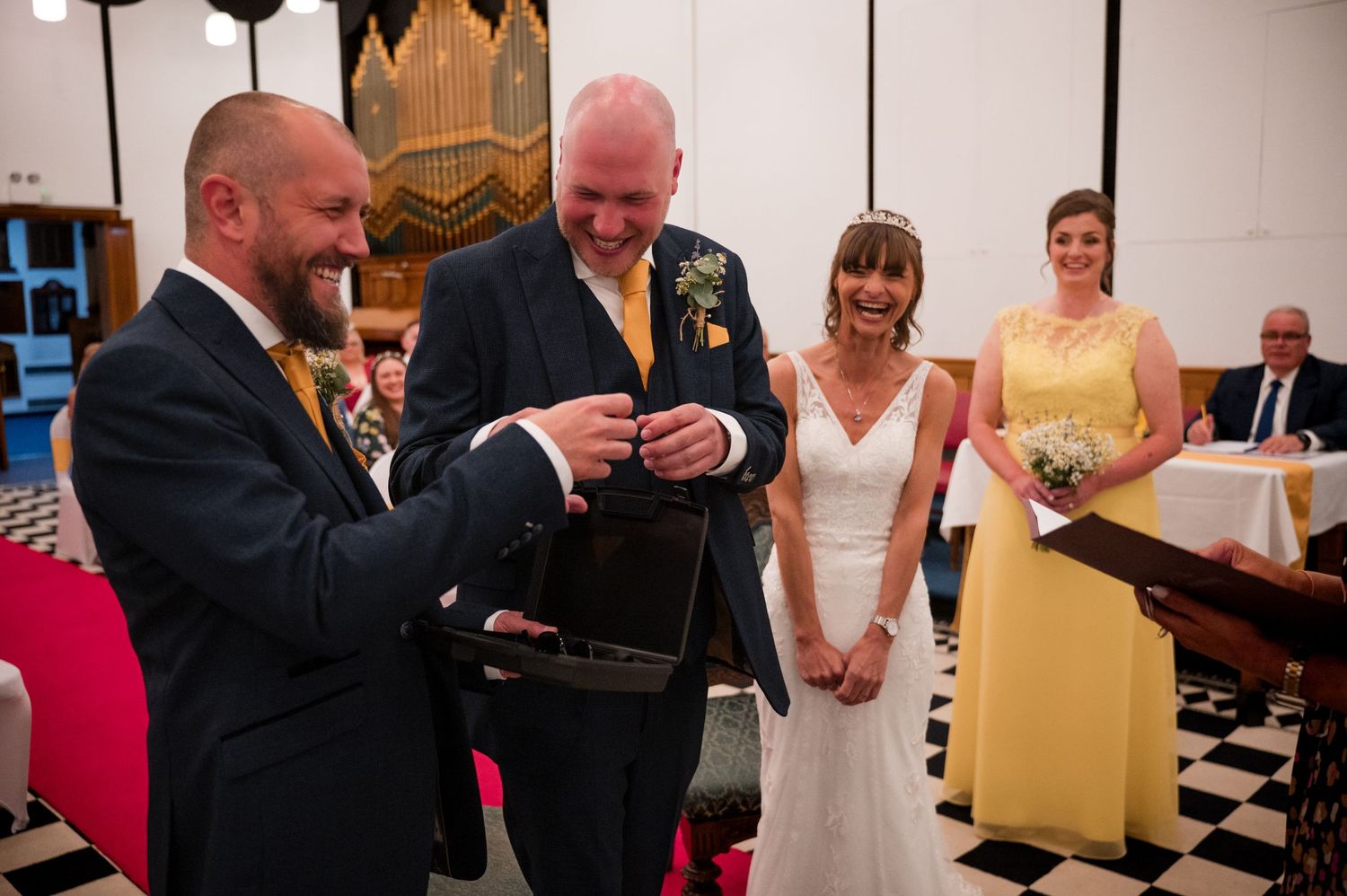 A row of wedding guests reading from yellow paper programs during a church ceremony.