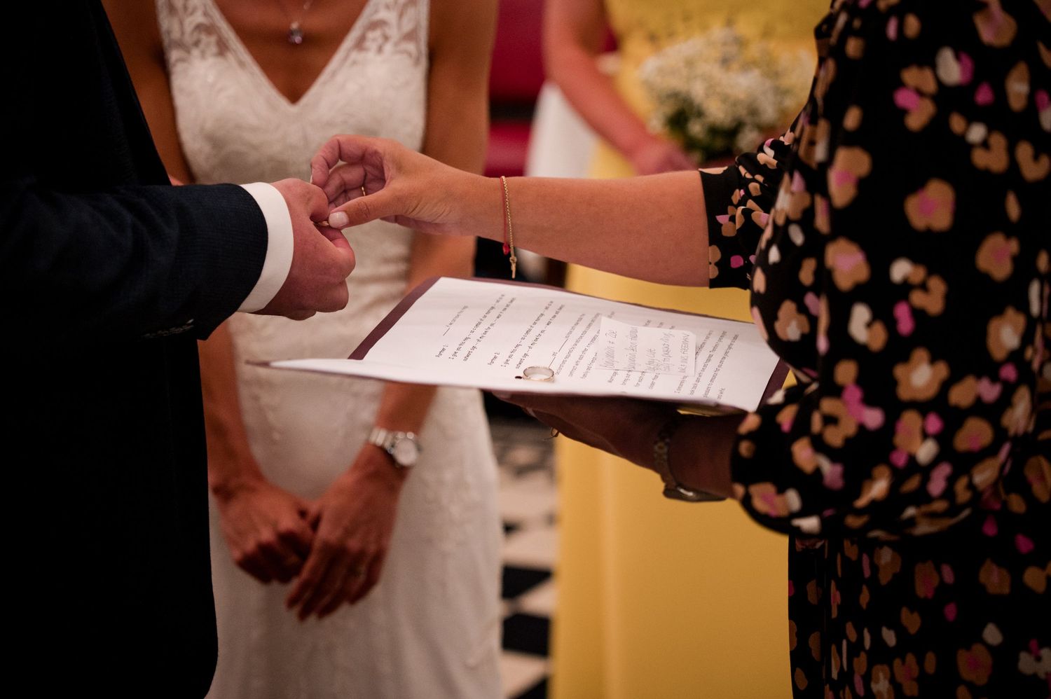 Close-up shots of hands holding papers and signing documents during a wedding ceremony.