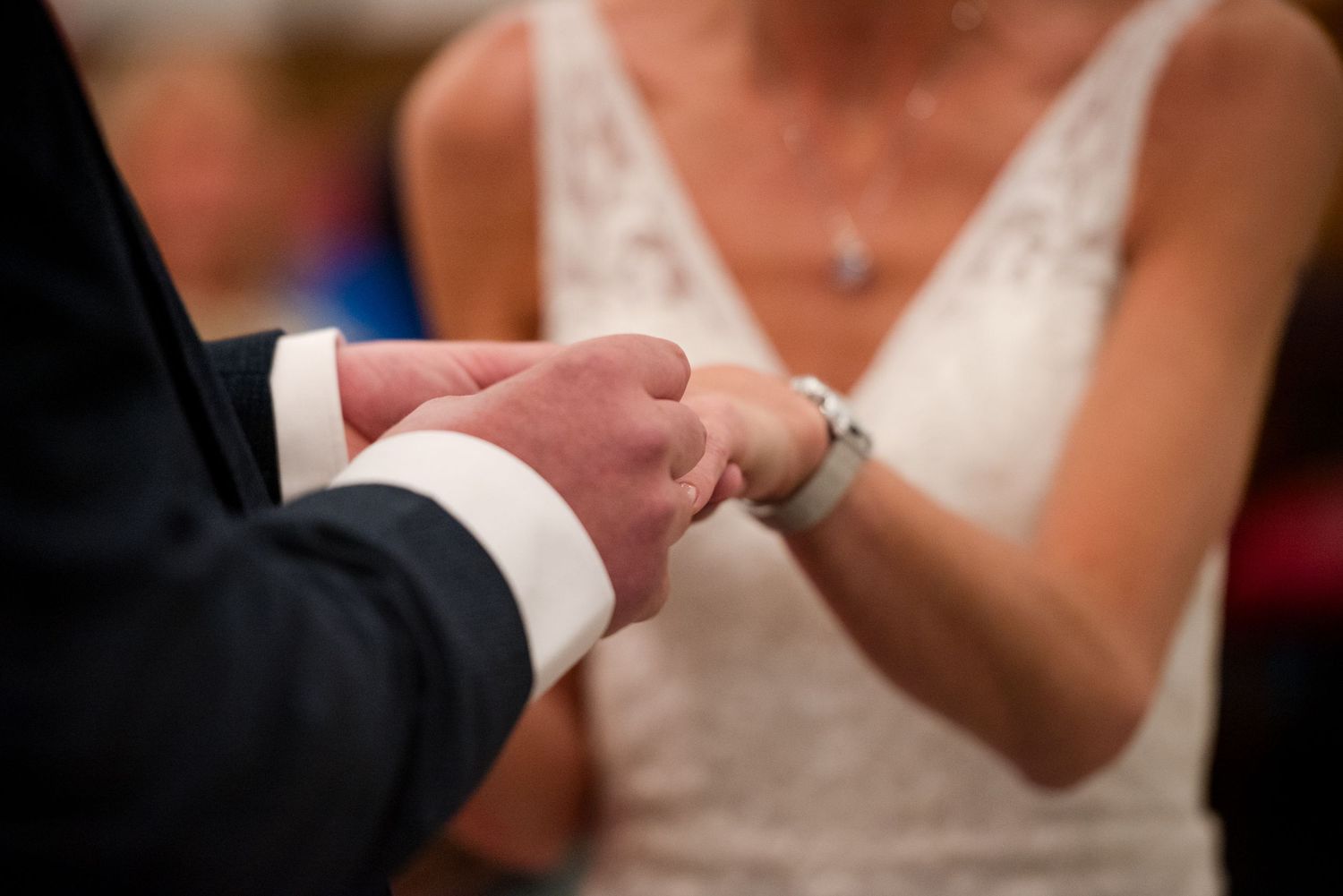 Close-up photo of a couple's hands during a wedding ceremony as they exchange rings.