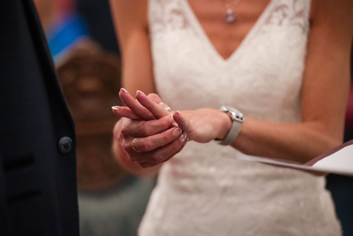 Wedding ring ceremony closeup showing hands exchanging rings during traditional marriage vows.