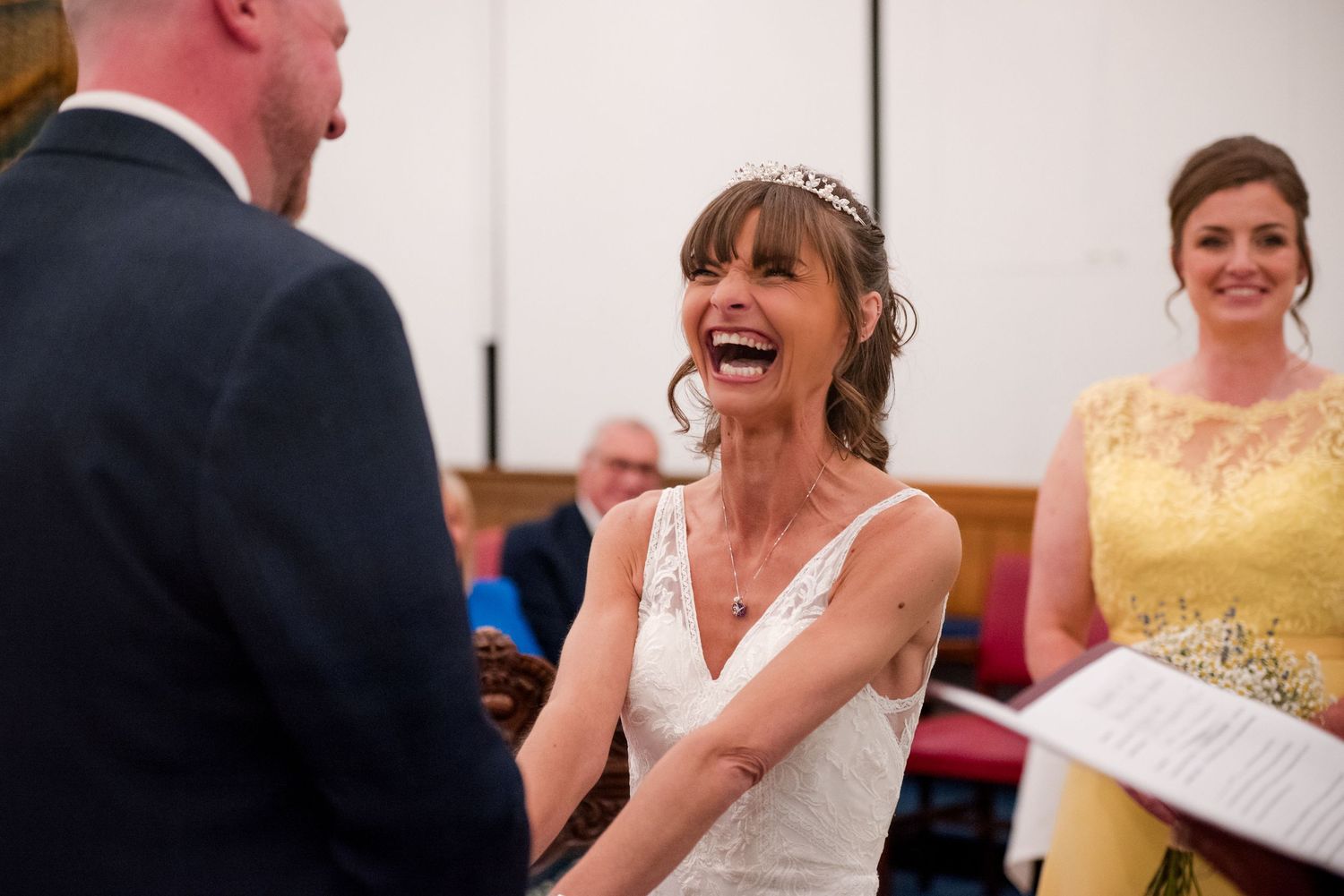 Wedding guests laugh and smile together during a joyful reception celebration.
