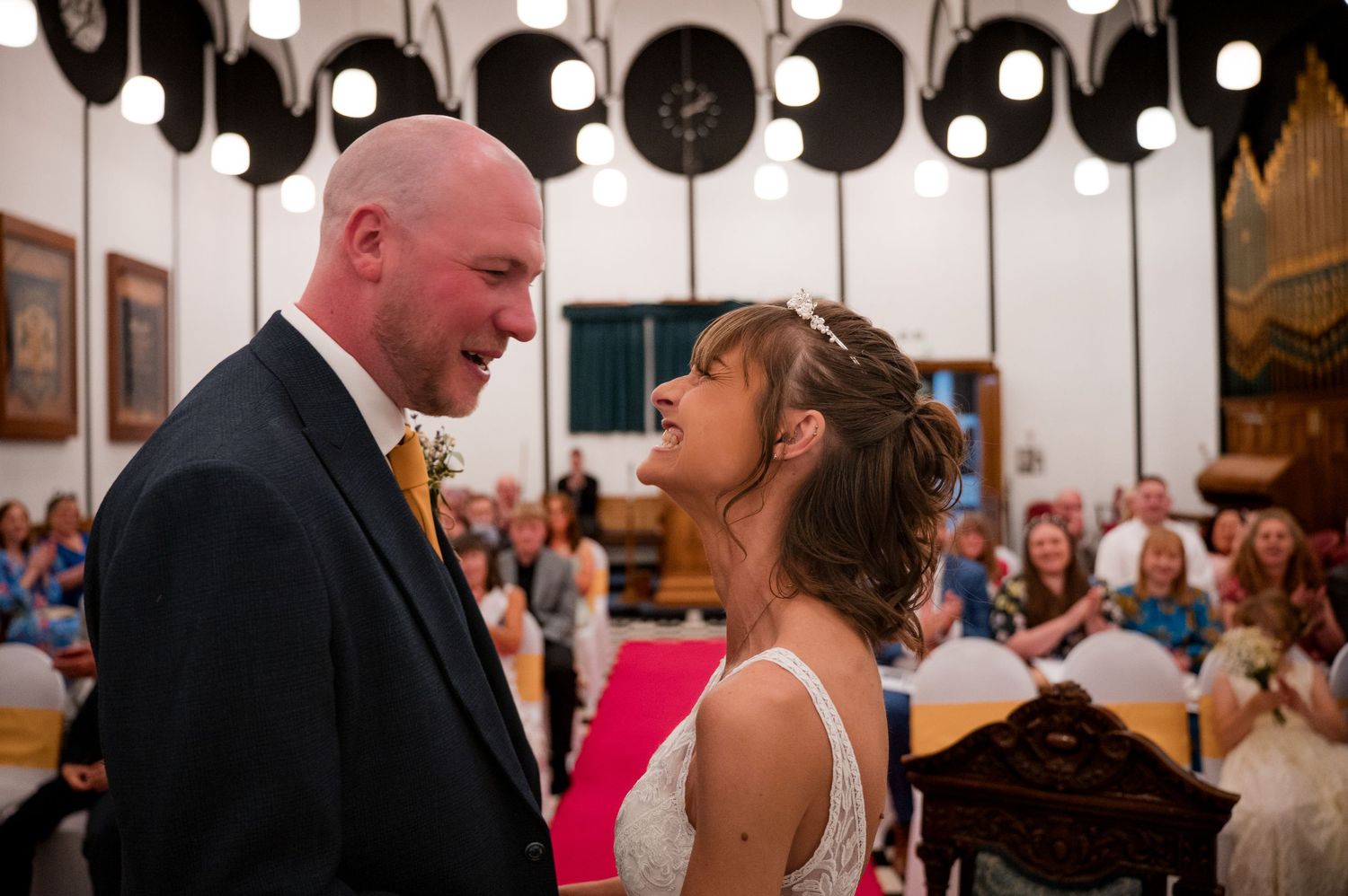A couple shares a romantic dance together at a wedding reception with other guests in the background.