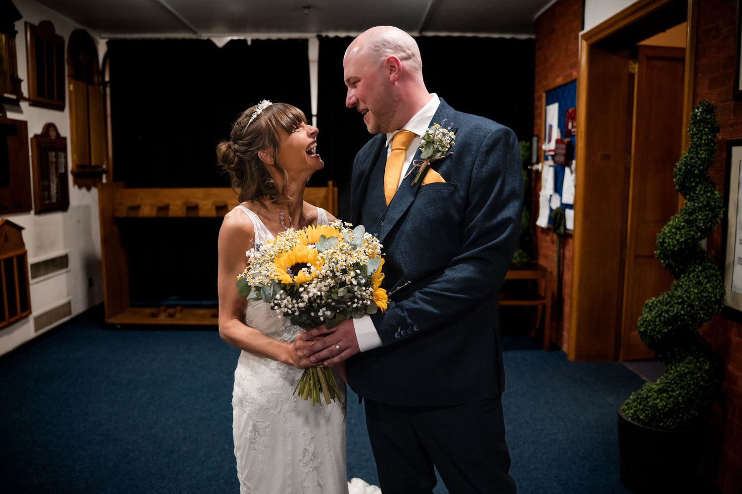 A couple shares a tender moment during their wedding ceremony in a rustic wooden church interior.
