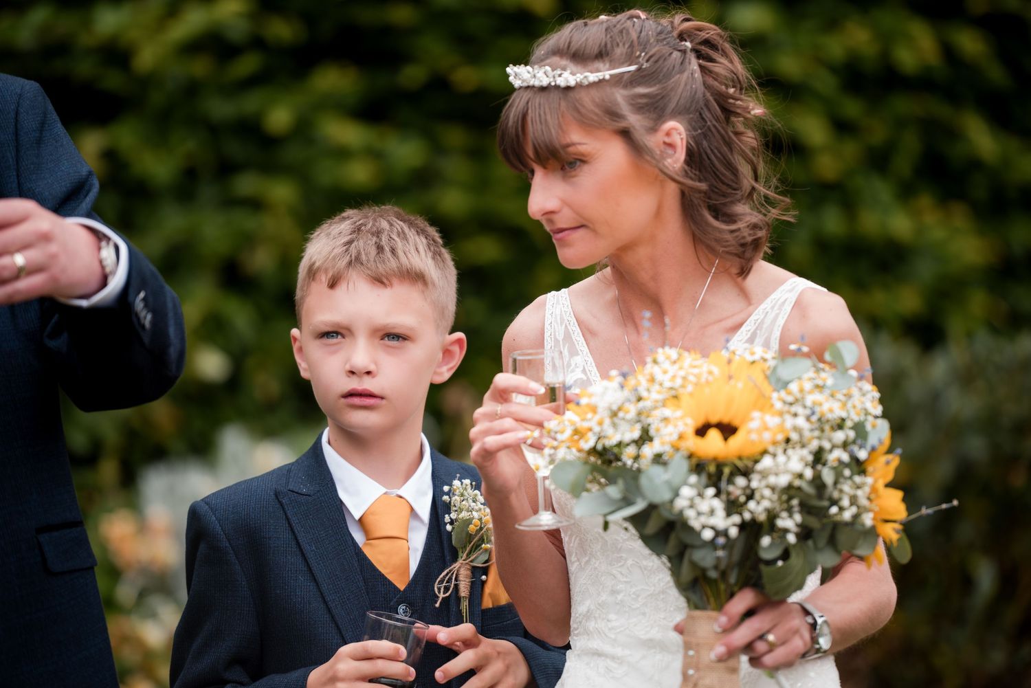 Guests and wedding party gather for candid moments in garden setting with sunflowers.