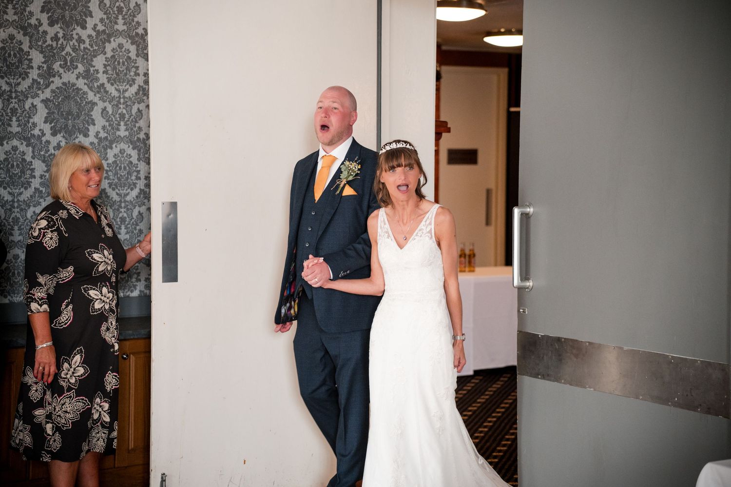 A couple shares a tender moment in a hallway during their wedding celebration.