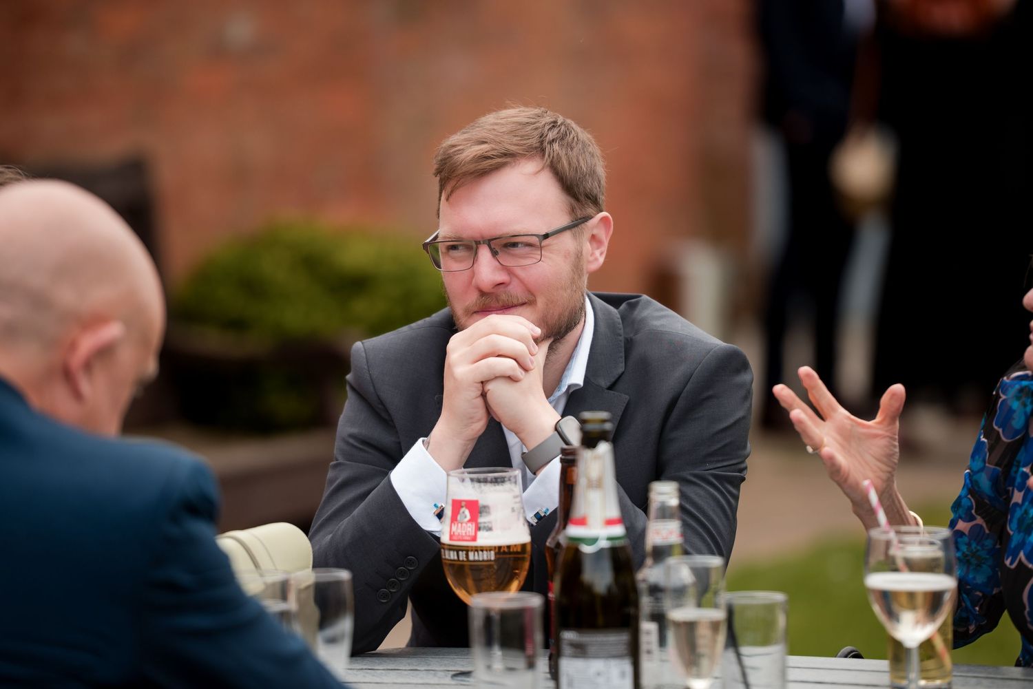 People engaged in conversation at a table with drinks and glasses during what appears to be a social gathering.