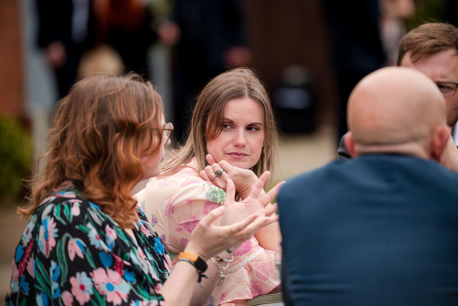 A group of people sitting together at an outdoor gathering with blurred background elements.