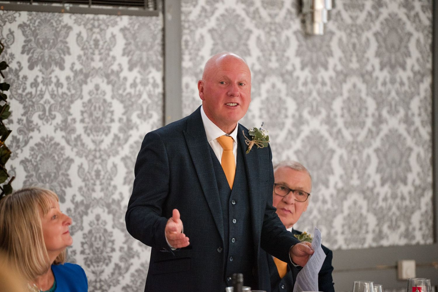 A series of candid photos showing people in formal attire against a gray damask wallpaper background at an event.