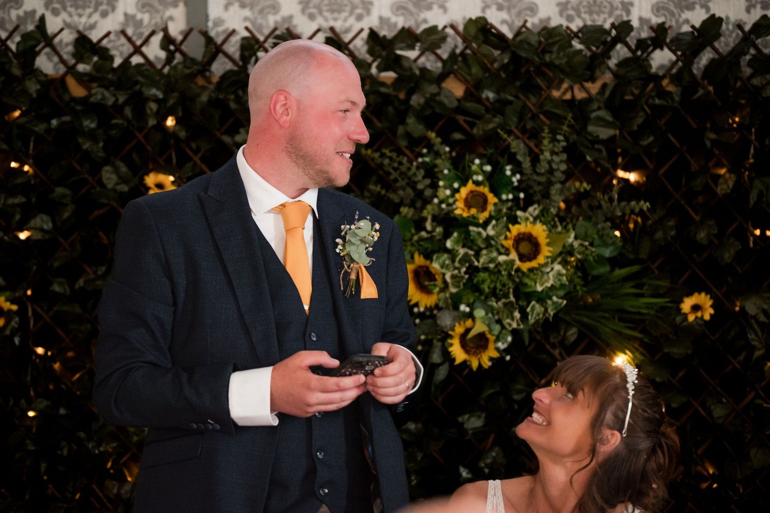 A couple celebrates their wedding ceremony in a garden setting with sunflowers in the background.