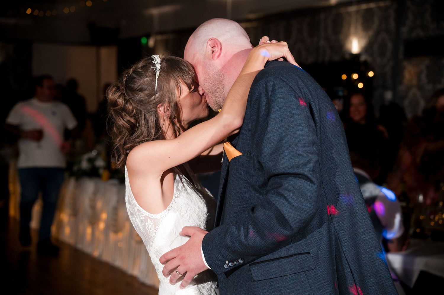 A couple shares a romantic dance together at a dimly lit wedding reception venue.