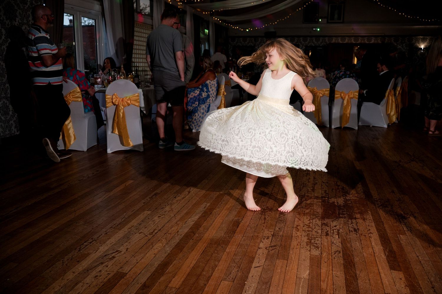 People dancing together on a wooden dance floor at a wedding reception celebration.