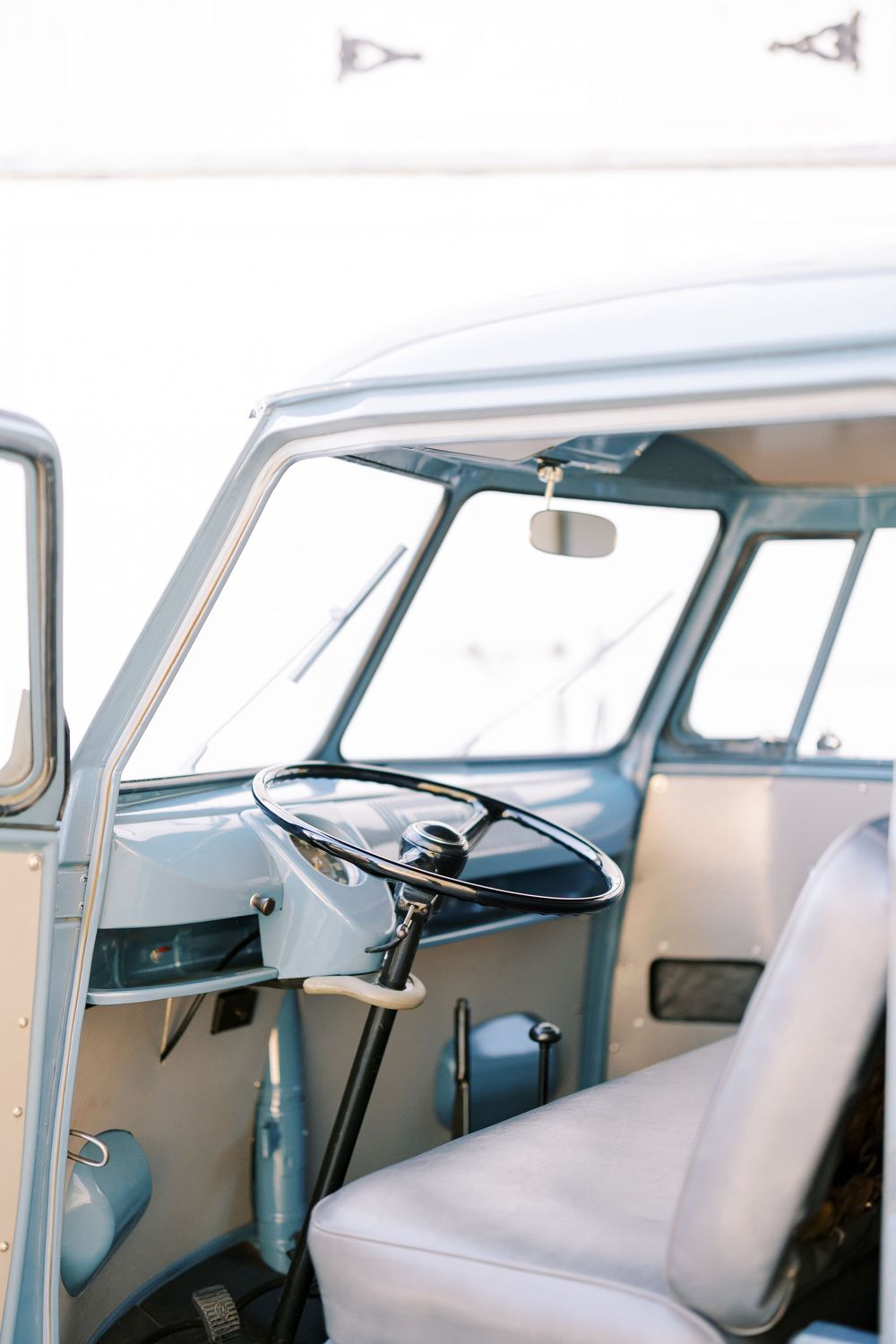 Interior view of a classic Volkswagen van showing white seats and dashboard details.