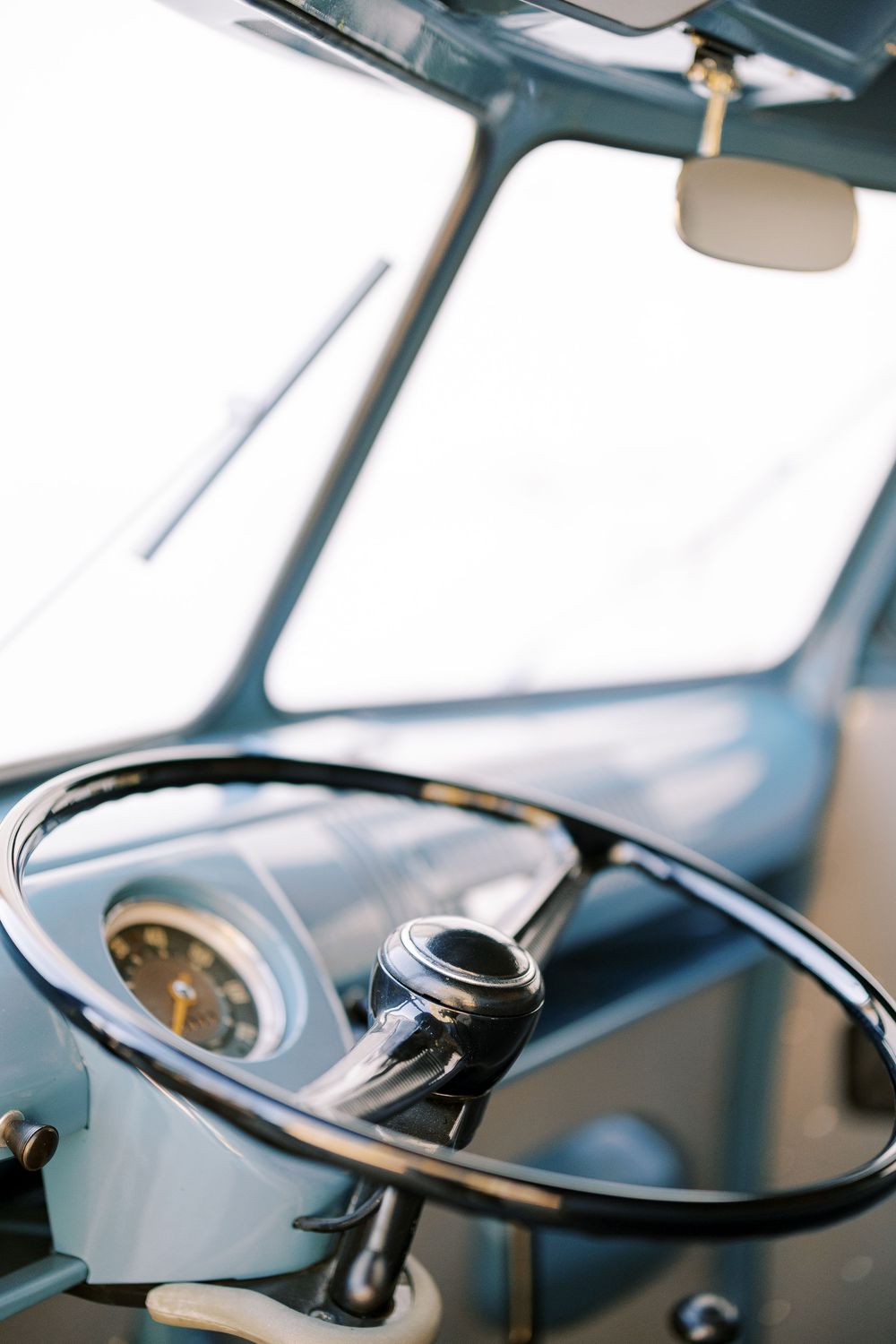 Interior view of a classic car dashboard showing the steering wheel and gauges.