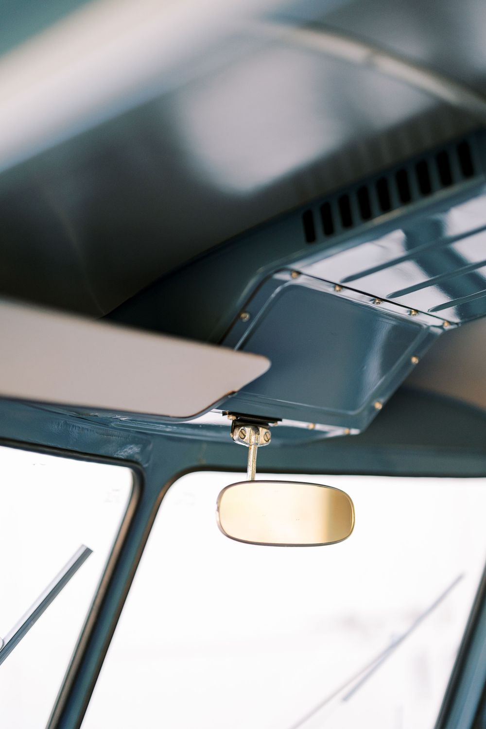 Close-up view of a car interior showing a rear view mirror mounted on the windshield in natural lighting.