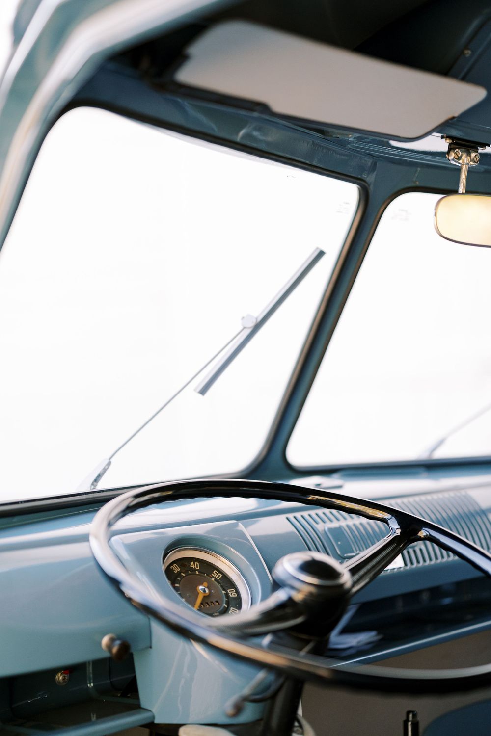 Wide angle view of a classic Volkswagen van interior showing steering wheel and windshield.