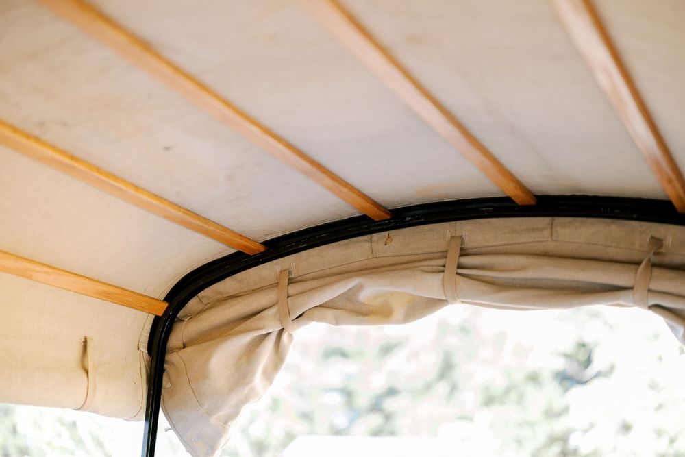 White canvas canopy or tent roof with wooden support beams creating an overhead shelter structure.
