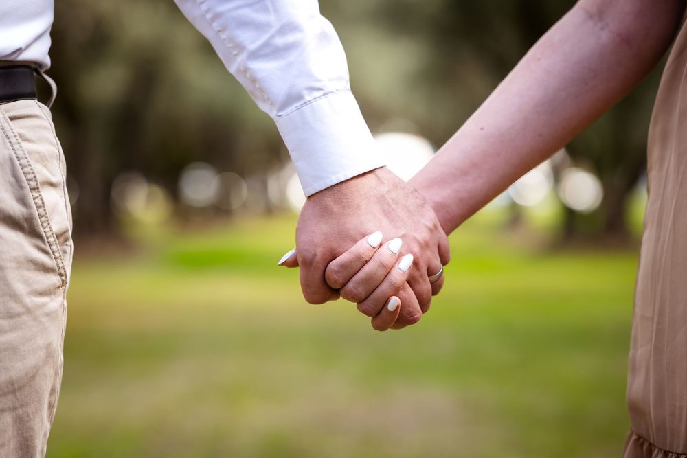 Couple holding hands outdoors in a park, showcasing unity and love.