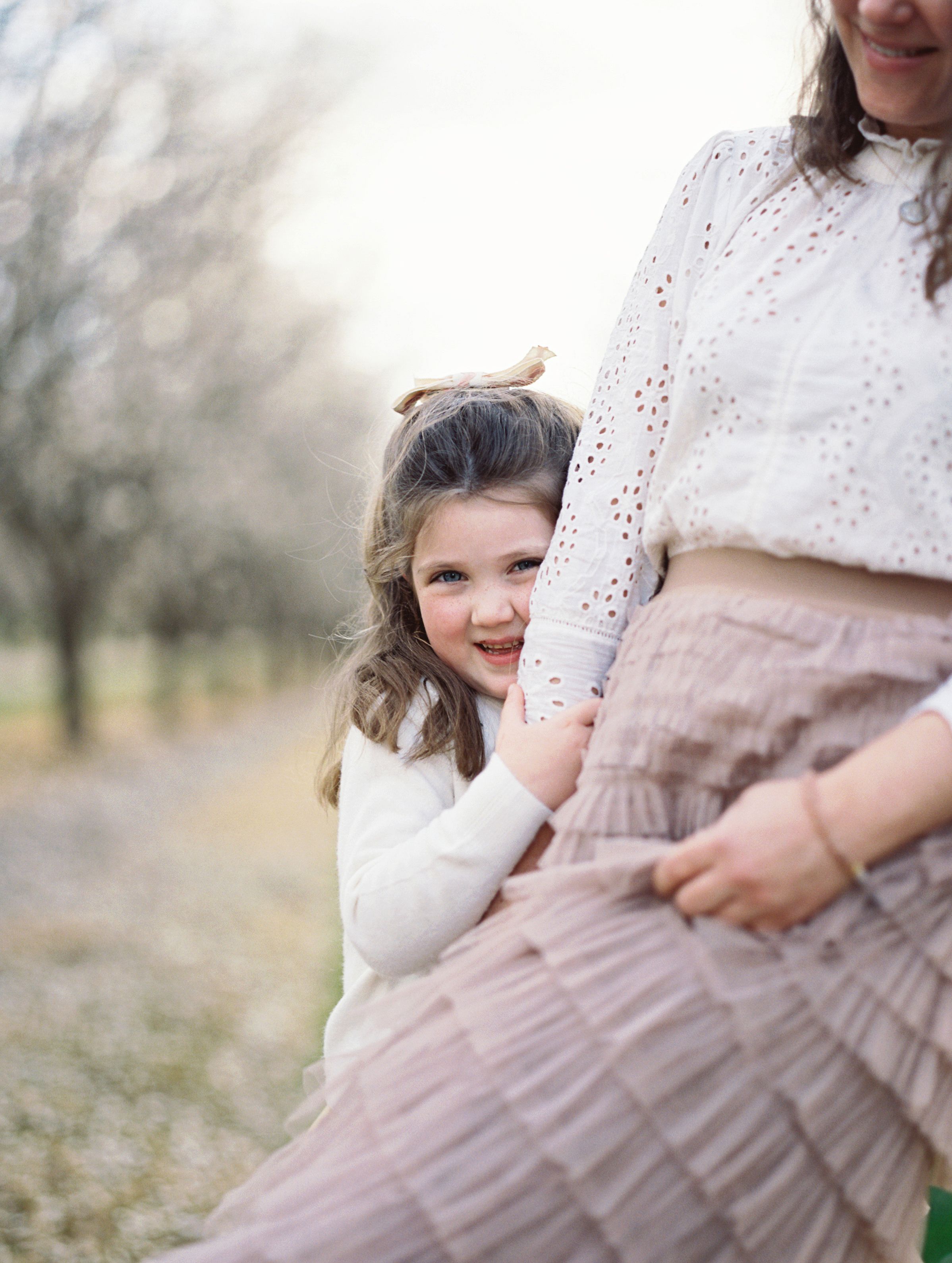 Tender moment captured in soft lighting with white eyelet lace details.