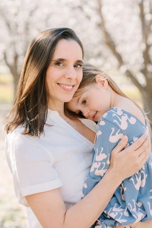 Mother and child sharing sweet embraces against a bright outdoor backdrop.