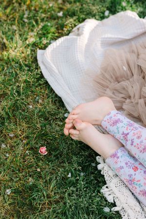 Floral dress and tulle skirt details laying on green grass in sunlight.