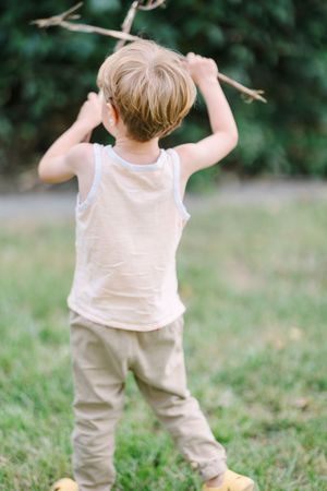 Child in white clothing running and playing in a grassy outdoor setting.