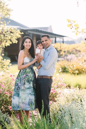 A family poses together in a garden with blooming flowers during golden hour.