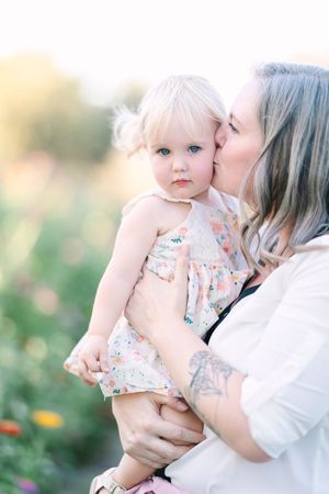 Tender moments captured in soft light with floral details and natural outdoor setting.