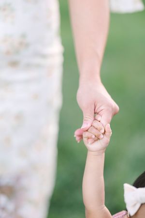 Close-up of hands holding together during an outdoor family photoshoot.