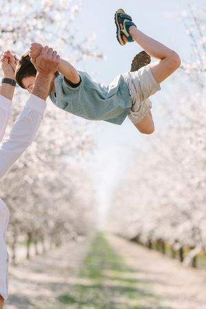 People jumping joyfully under blooming cherry blossom trees.
