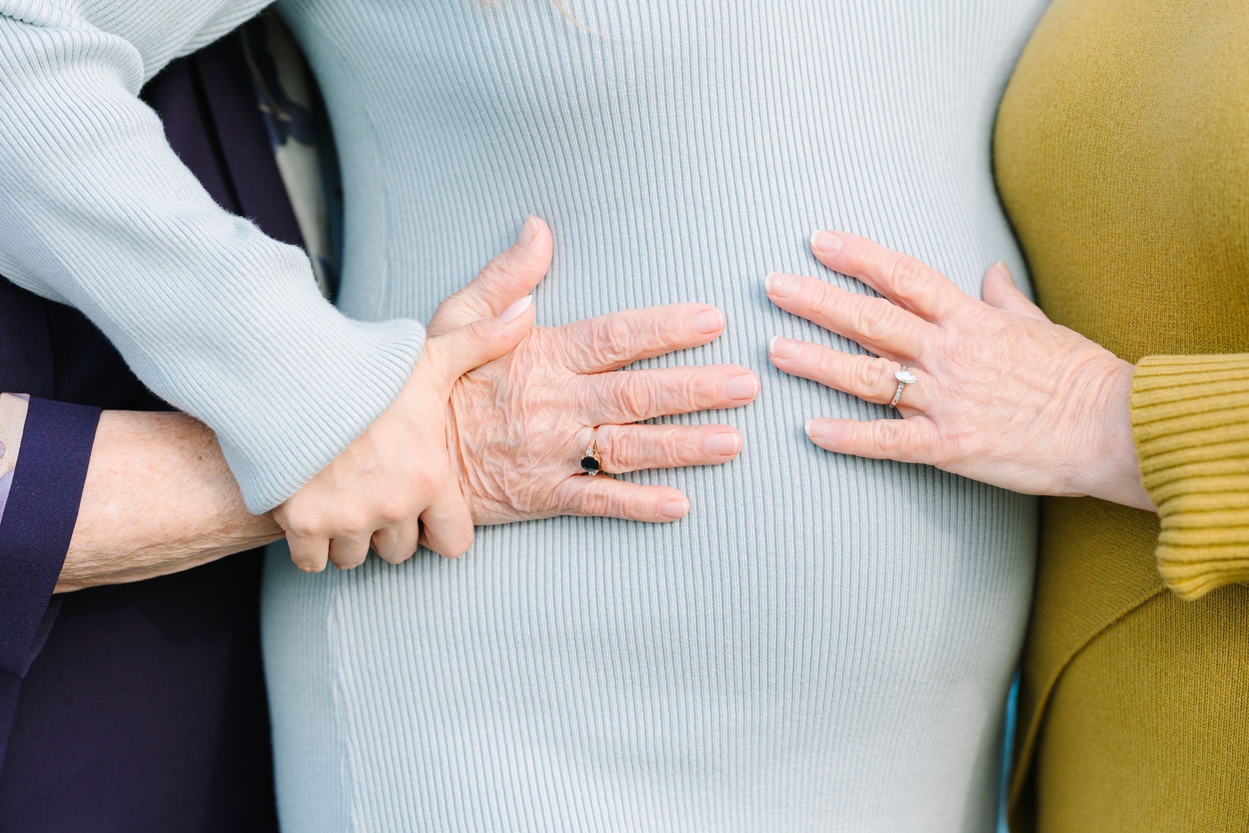 Close-up shots of hands gently cradling a pregnant belly in a gray top.